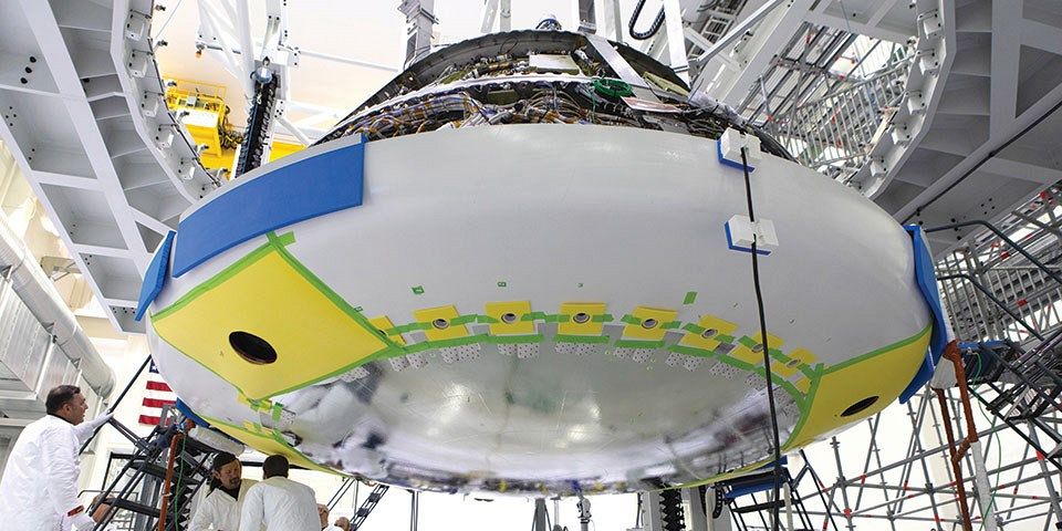 Lockheed Martin engineers and technicians install the titanium heat shield to the Orion crew module on 25 July 2018 at NASA’s Kennedy Space Center in Florida. Photo: NASA/Kim Shiflett