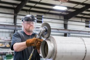A welder cleans the welds on a Vacuum Jacketed Piping system. Photo ©ACME Cryogenics/OPW Clean Energy Solutions